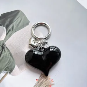 Detailed shot of a sleek black heart keychain with silver metal ring and small charm.