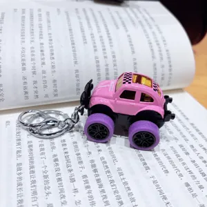 Close-up shot of a cute pink monster truck keychain with purple wheels resting on an open book page.