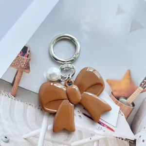 Brown acrylic bow keychain with white pearl and silver metal clasp for keys or bags.
