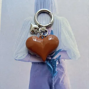 Close-up detail of the glossy brown heart keychain pendant with silver metal ring and clasp.