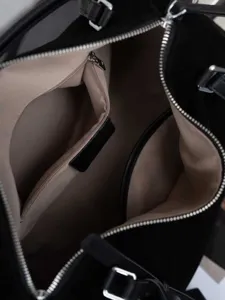 Black suede tote bag interior detail shot showing lining and zipper pocket for daily commute.