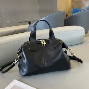 Close-up detail of black leather handbag showcasing fine texture and polished metal hardware.