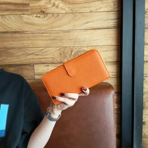 Orange pebbled leather long wallet featuring a secure flap closure and zip around design for women.