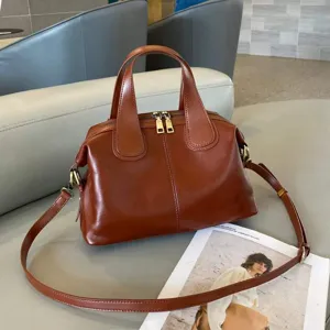Detailed view of brown genuine leather shoulder bag featuring top handles and secure zipper.