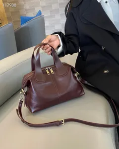 Genuine leather dumpling handbag in burgundy, featuring dual zippers and adjustable crossbody strap.