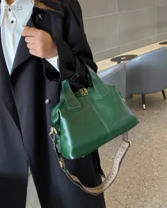 Dark green genuine leather dumpling bag detail, showing premium oil-wax texture and wide strap.