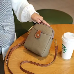 Close-up detail of genuine leather mini crossbody phone bag with snap closure and strap.