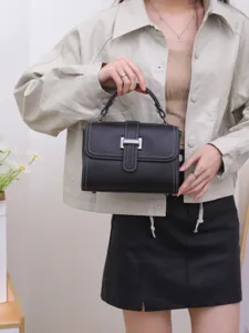 Classic black leather top handle bag with flap closure and metallic lock for women commuting.