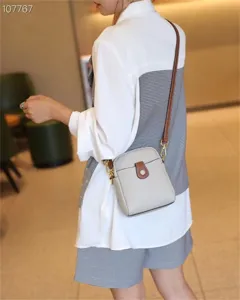 Detailed view of the mini leather crossbody phone bag in light grey, showcasing the brown strap.