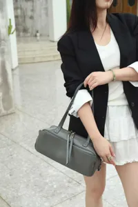 Minimalist leather bowling bag for women, stylish grey Boston handbag with top handles and strap.