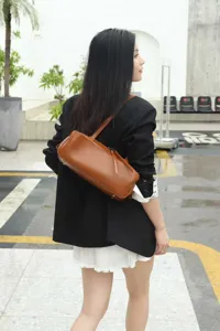 Detailed view of brown leather bowling bag worn on shoulder with minimalist fashion style