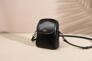 Black genuine leather vertical phone bag detail, compact crossbody design with stylish hardware.