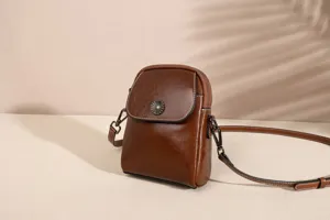 Detail view of brown leather multi-layer cross-body phone bag with delicate flower clasp.