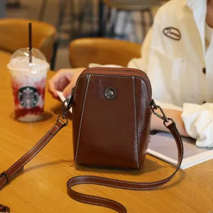 Sac bandoulière compact pour téléphone en cuir ciré avec détails métalliques élégants.