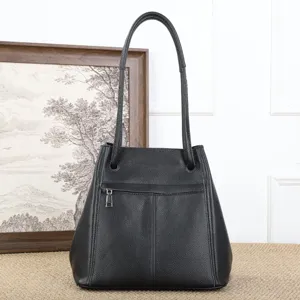 Detail view of a black leather bucket bag featuring slim straps and a front zipper pocket.