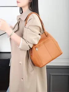 Detailed view of the brown leather shoulder bag worn by a model, showing texture and zipper.
