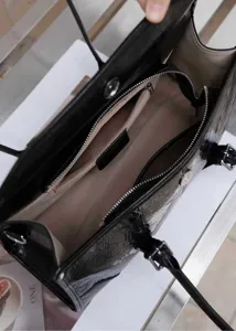 Vista interna dettagliata di una borsa a tracolla nera in pelle scrostata con scomparti.
