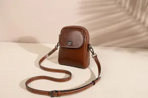 Detailed view of a brown leather mini crossbody phone bag with adjustable strap and chic buckle.