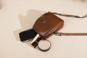 Close-up detail of women's brown leather crossbody phone bag with multi-layer compartments.