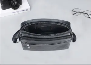 Vista detallada del bolso bandolera negro de cuero genuino para hombre con múltiples bolsillos.
