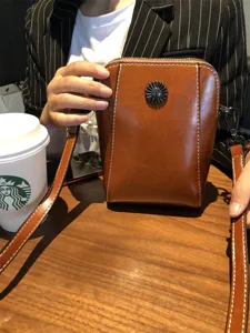 Brown leather crossbody phone bag with retro design, metal flower decor, and strap.