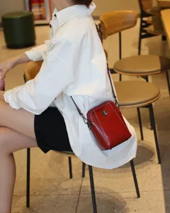 Vue détaillée d'un mini sac bandoulière en cuir ciré rouge avec rivet soleil en métal.
