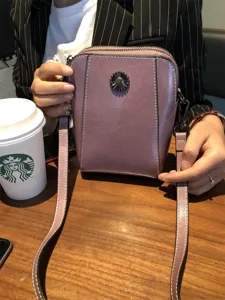 Detail view of the women's leather crossbody phone bag featuring a metal flower button and strap.