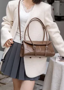 Dettaglio di una borsa a spalla vintage marrone in pelle verniciata a doppia cinghia.