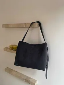 Minimalist dark suede shoulder bag for women, spacious daily commuter tote with long strap.