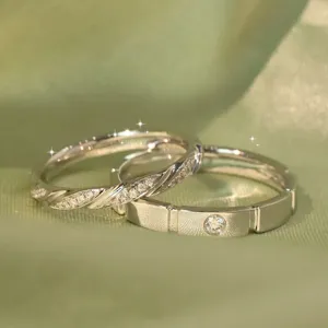Close-up detail of silver couple rings set with sparkling diamonds on green satin.