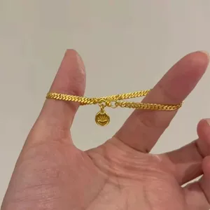 Gros plan détail du bracelet gourmette en or avec pendentif rond mignon pour style chic.