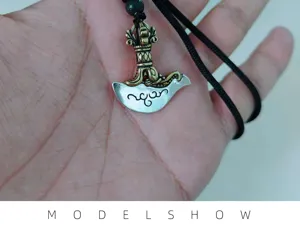 Close-up detail shot of a vintage double-color vajra axe pendant necklace with black cord.