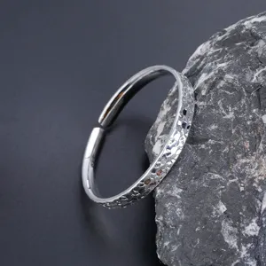 Strukturierter offener silberfarbener Armreif Detailaufnahme, minimalistisches Mode-Schmuck-Design.
