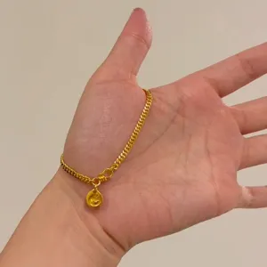 Gros plan sur le bracelet chaîne cubaine doré avec charm mignon, bijou de poignet élégant.