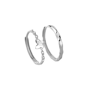 Silver couple rings detail shot, butterfly decor, twisted band design, minimalist style.