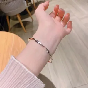 Gros-plan d'un bracelet jonc en métal massif motif Möbius porté au poignet, design élégant.