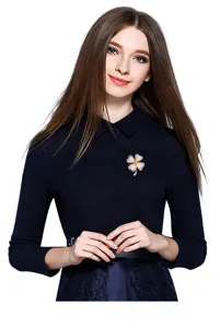 Detailed view of a sparkling four-leaf clover brooch worn elegantly on dark clothing.