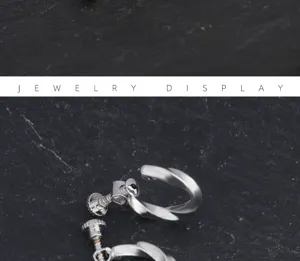 Primer plano de pendientes de rosca twist Mobius plateados, joyería minimalista para hombre.