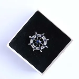 Primo piano dettagliato di una bellissima spilla a forma di timone nautico con strass.