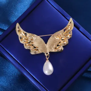 Close up view of the gold tone angel wing brooch with a hanging pearl detail, exquisite design.