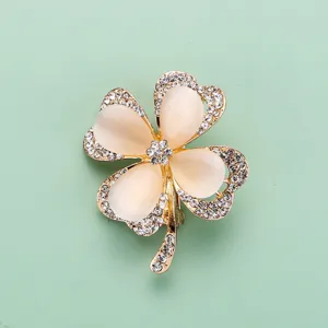Vue détaillée d'une broche trèfle à quatre feuilles, métal doré et strass étincelants.