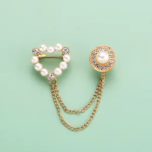 Gros plan sur la broche double en perles et strass dorées pince cardigan épingle de sûreté