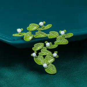 Dettaglio spilla perla foglia pianta verde con squisita texture smalto ed eleganza.