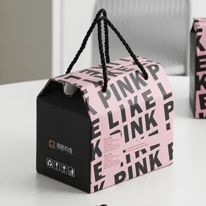 Caja de regalo en negro y rosa con asa, presentación elegante para artículos variados.