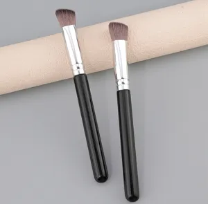 Closeup of slanted makeup brushes with black handles for precise highlighter and concealer.