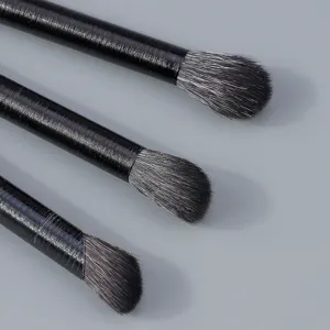 Close-up detail of three professional eye makeup brushes with black handles and soft bristles.