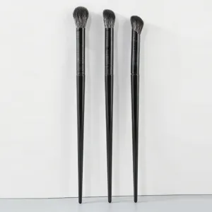 Detail view of three professional black makeup brushes with soft bristles for eye shadow blending.