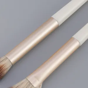 Detail van de professionele make-up kwast met zachte haren en een gouden huls.