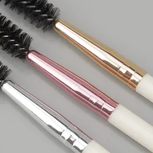 Close-up detail of double-ended spiral makeup brushes with metallic gold, pink and silver handles.