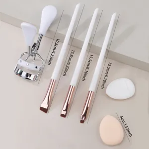 Detailed view of cosmetic tool set including three makeup brushes, eyelash curler and sponge pads.